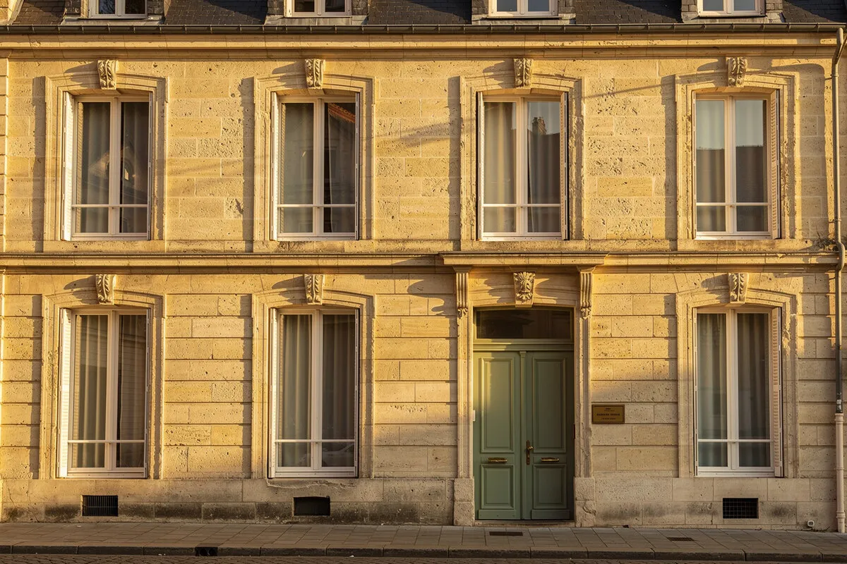 Façade en pierre de Caen de l'Étude Notariale Vauquelin, porte sage, lumière dorée